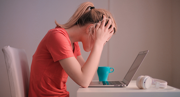junges Mädchen verzweifelt vor einem Laptop